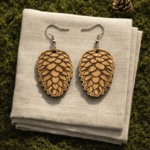 kolczyki w kształcie szyszki leżące na lnianej chustcd